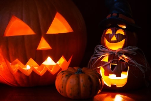 A group of lit candles sitting next to some pumpkins.