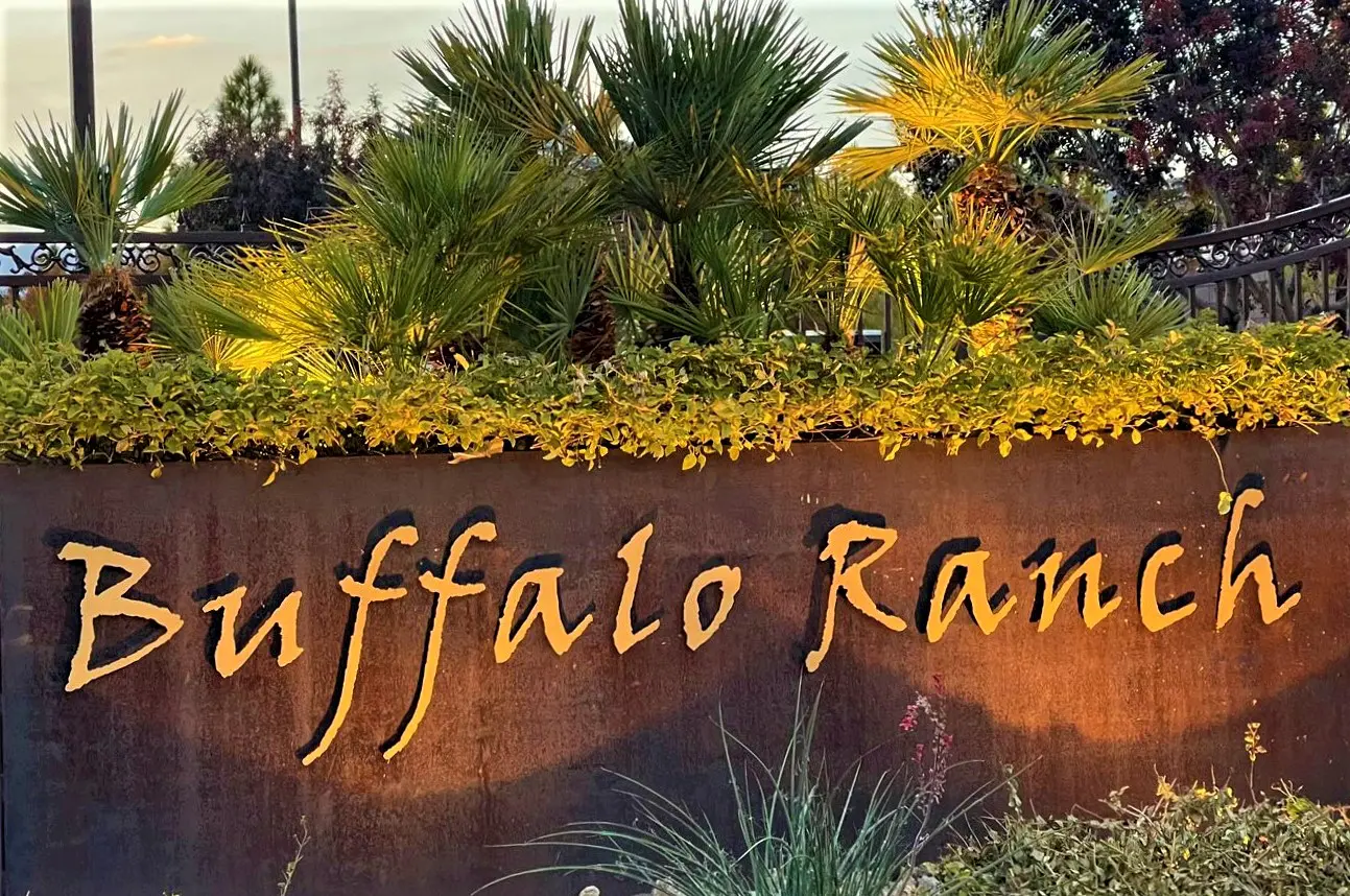 A sign that says buffalo ranch with some plants in the background