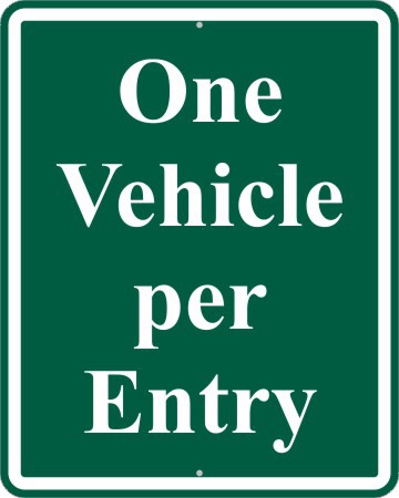 A green sign with white lettering that says one vehicle per entry.