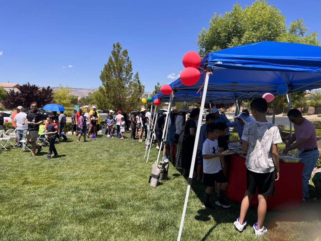 A group of people standing around tents on the grass.