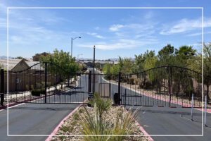 A gated driveway with a fence and plants in the foreground.