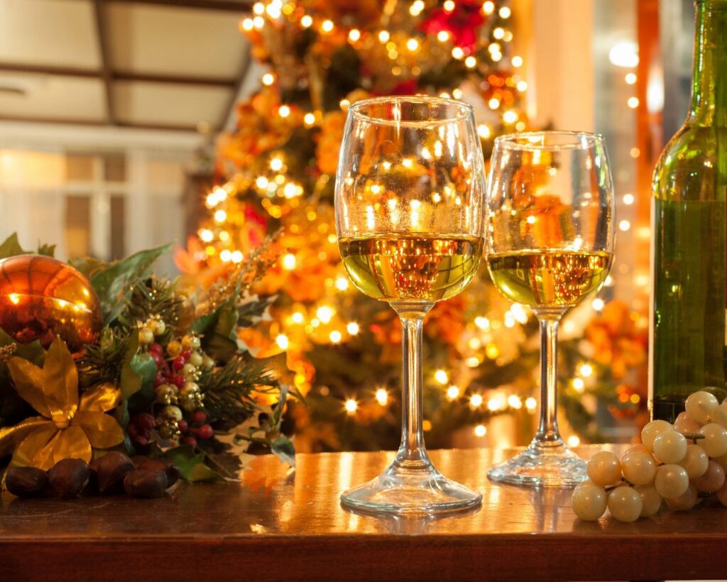 Two wine glasses sitting on a table in front of a christmas tree.