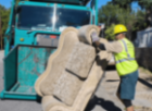 A man in yellow vest and hard hat carrying a large piece of concrete.