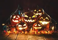 A group of pumpkins with faces lit up for halloween.