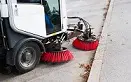 A street sweeper truck parked on the side of a road.