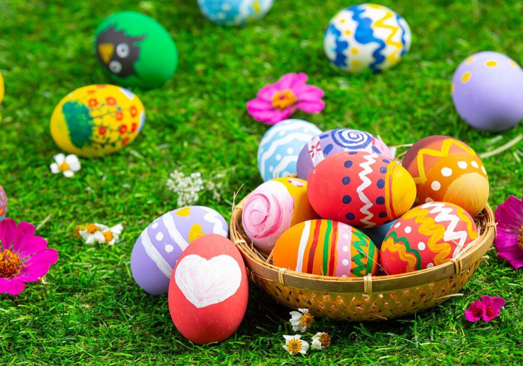 A basket of colorful eggs on the grass.