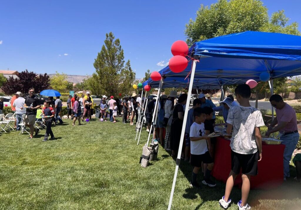 A group of people standing around tents on the grass.