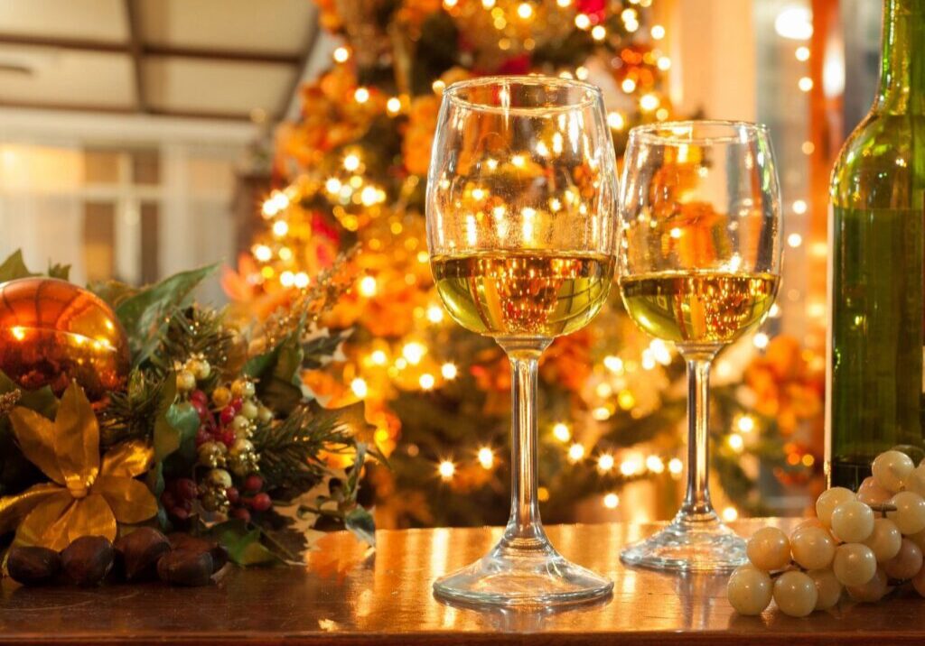 Two wine glasses sitting on a table in front of a christmas tree.